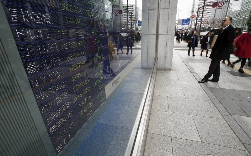 © Reuters. A pedestrian looks at an electronic board outside a brokerage in Tokyo