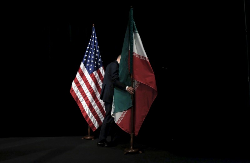 © Reuters. A staff member removes the Iranian flag from the stage after a group picture with foreign ministers and representatives during the Iran nuclear talks at the Vienna International Center in Vienna