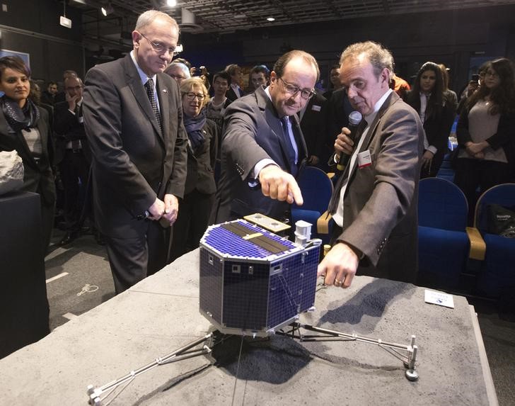 © Reuters. CNES president Le Gall, French President Hollande and astrophysicist Rocard inspect a scale model of Rosetta lander Philae as they visit the Cite des Sciences at La Villette in Paris