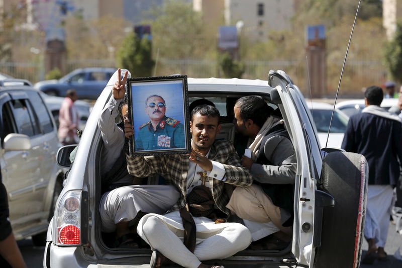 © Reuters. A man holds a picture of Yemen's former President Ali Abdullah Saleh as he rides a car in Sanaa, Yemen