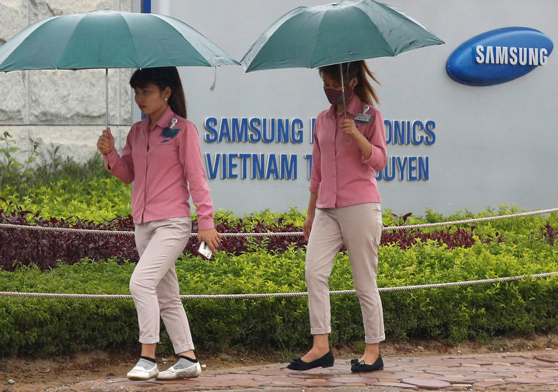 © Reuters. An employee holds a smartphone as she is on the way to work at the Samsung factory in Thai Nguyen province, north of Hanoi