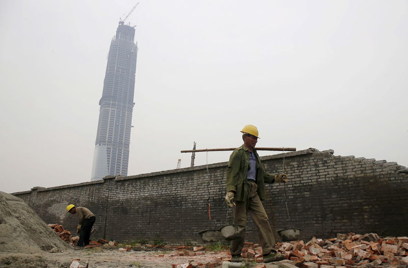 © Reuters. Labourers work at the construction site of an official building next to the unfinished 438-metre-high Wuhan Centre in Wuhan