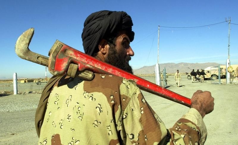 © Reuters. MUJAHADEEN FIGHTER CARRIES LARGE PIPE WRENCH AT KANDAHAR AIRPORT.