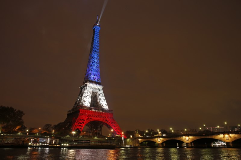 © Reuters. The Eiffel Tower is lit with the blue, white and red colours of the French flag in Paris to pay tribute to the victims of a series of deadly attacks in the French capital