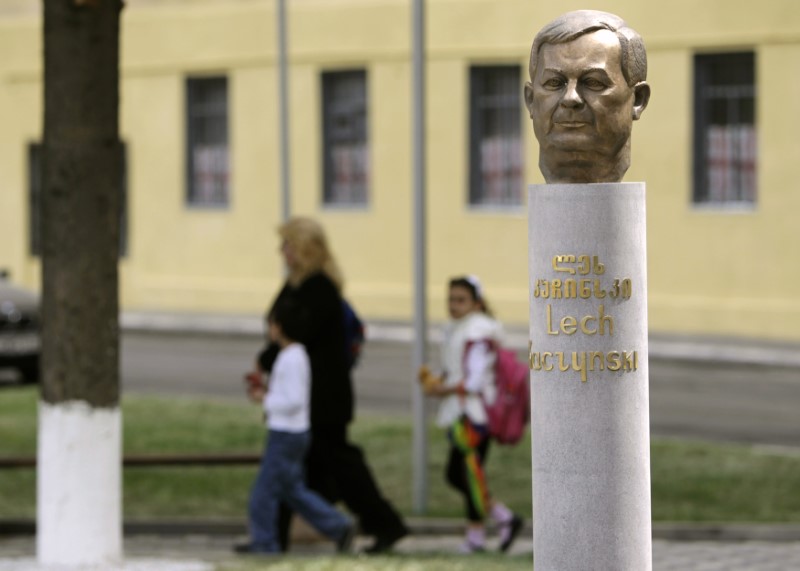 © Reuters. Pedestrians walk past a monument of late Polish President Lech Kaczynski in Tbilisi