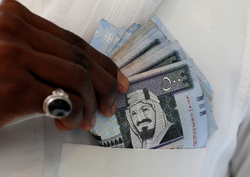 © Reuters. A Saudi man shows Saudi riyal banknotes at a money exchange shop in Riyadh