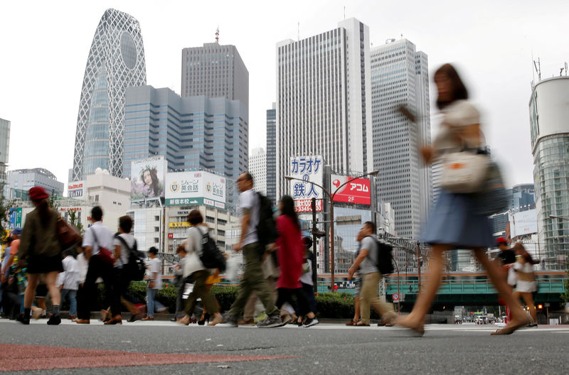 © Reuters. People cross a street in front of high-rise buildings in the Shinjuku district in Tokyo