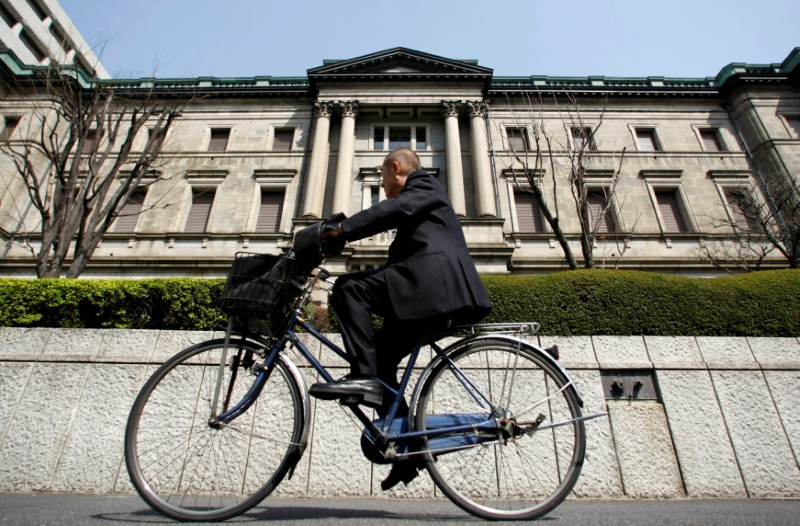 © Reuters. A man rides a bicycle past the BOJ building in Tokyo
