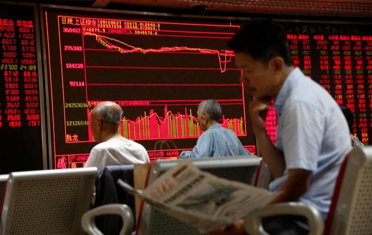 © Reuters. Инвесторы смотрят на электронное табло с данными об акциях в брокерской компании Пекина