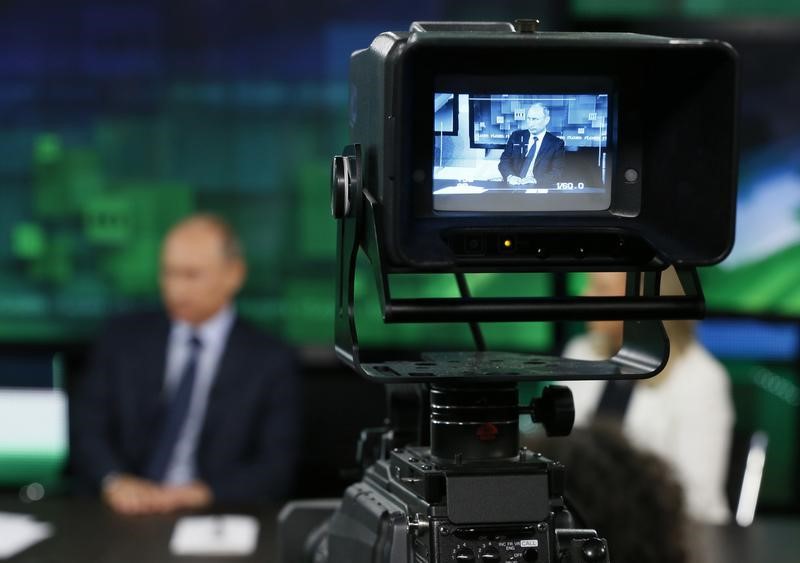 © Reuters. Russian President Vladimir Putin is seen on the screen of a television camera during his visit to the new studio complex of television channel 'Russia Today' in Moscow