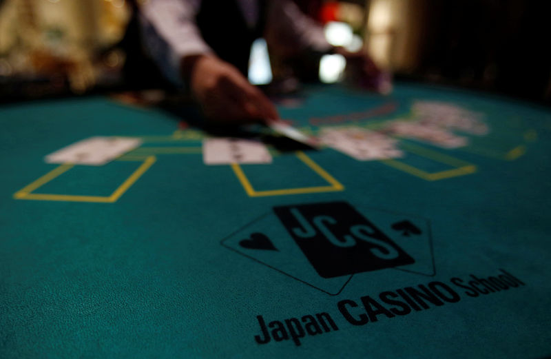 © Reuters. A logo of Japan casino school is seen as a dealer puts cards on a mock black jack casino table during a photo opportunity at an international tourism promotion symposium in Tokyo