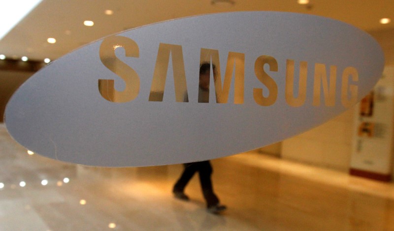 © Reuters. A man walks behind a logo of Samsung Electronics at the company's headquarters in Seoul