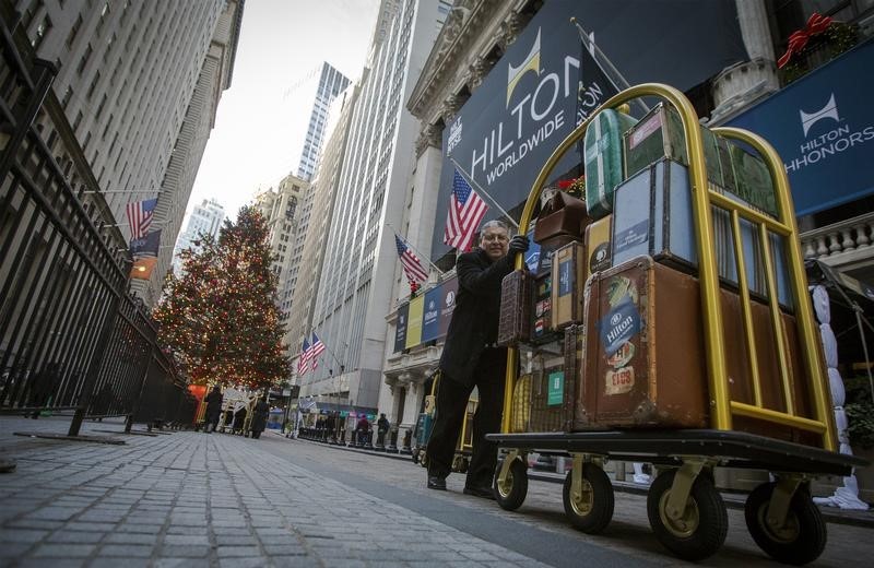 © Reuters. A Hilton employee pushes a luggage cart in front of the the New York Stock Exchange to celebrate of the company's IPO