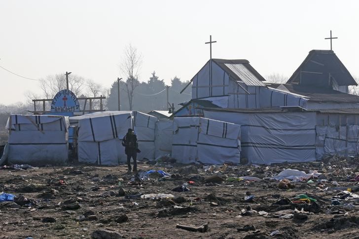 © Reuters. FILE PHOTO - A migrant walks past the church in the dismantled aera of the camp for migrants called the "Jungle", in Calais