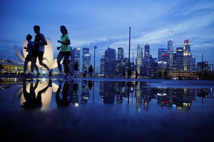 © Reuters. Joggers run past as the skyline of Singapore's financial district is seen in the background