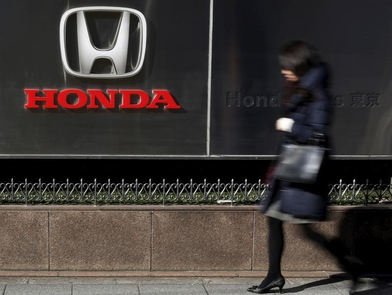 © Reuters. A woman walks past a logo of Honda Motor Co outside the company's dealership in Tokyo