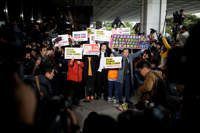 © Reuters. Protesters chant slogans as Choi arrives at a prosecutor's office in Seoul