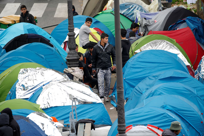 © Reuters. Migrants stand near their tents at a makeshift migrant camp on a street near the metro stations of Jaures and Stalingrad in Paris