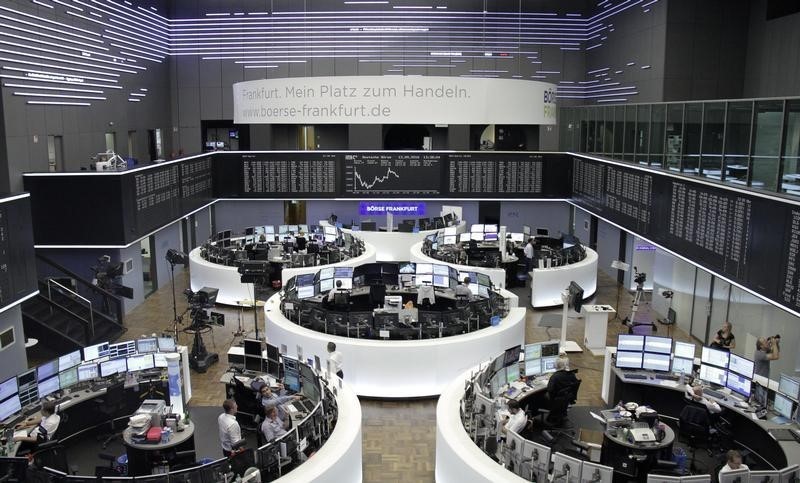 © Reuters. Traders work at their desks in front of the German share price index, DAX board, at the stock exchange in Frankfurt