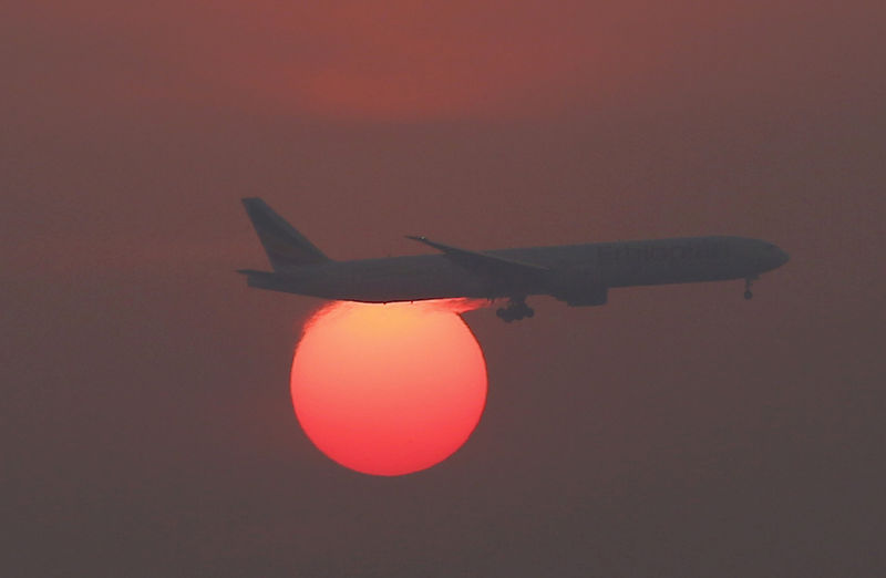 © Reuters. A plane flies over the setting sun in the sky at Beijing International Airport