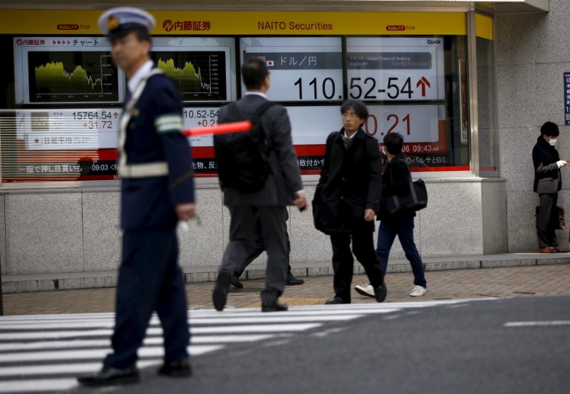 © Reuters. Electronic boards show the exchange rate between Japanese yen against the U.S. dollar as a police officer controls the traffic in front of a brokerage in Tokyo