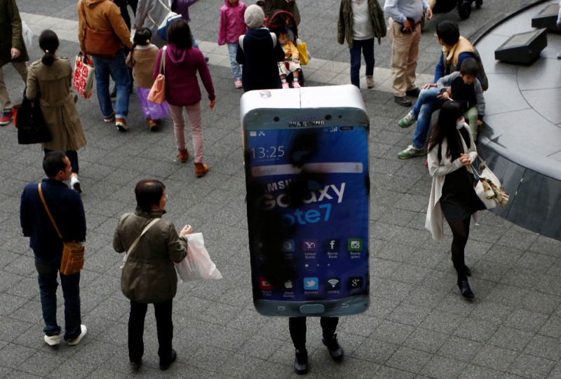 © Reuters. Participant wearing costume symbolising Samsung Galaxy Note 7 walks among pedestrians after a Halloween parade in Kawasaki