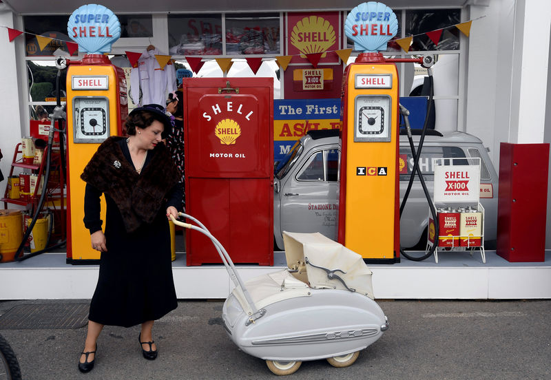 © Reuters. A woman holds the handle of a old pram in front of vintage Shell petrol pumps at the annual Goodwood Revival historic motor racing festival