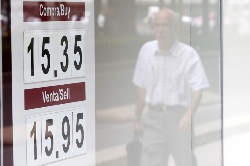 © Reuters. Man is reflected in window as he walks past a board displaying the exchange rate for the Mexican peso against the U.S. dollar at a foreign exchange house in Mexico City