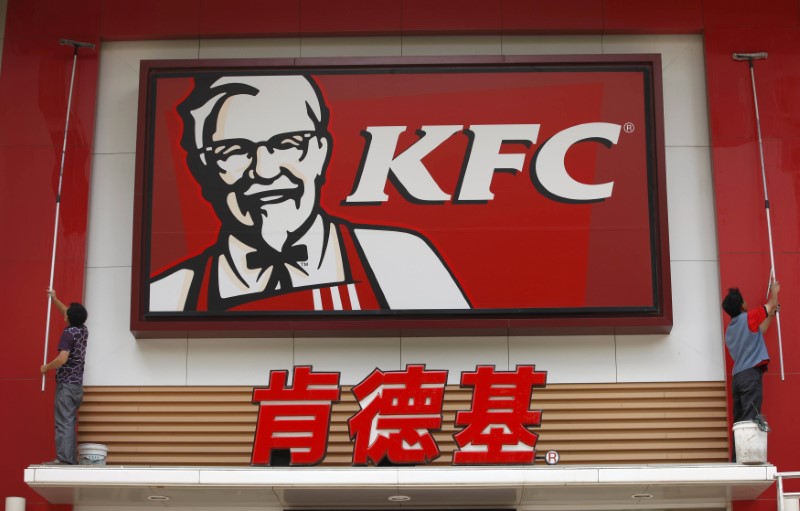 © Reuters. Labourers clean the external wall of a KFC restaurant in Huaibei