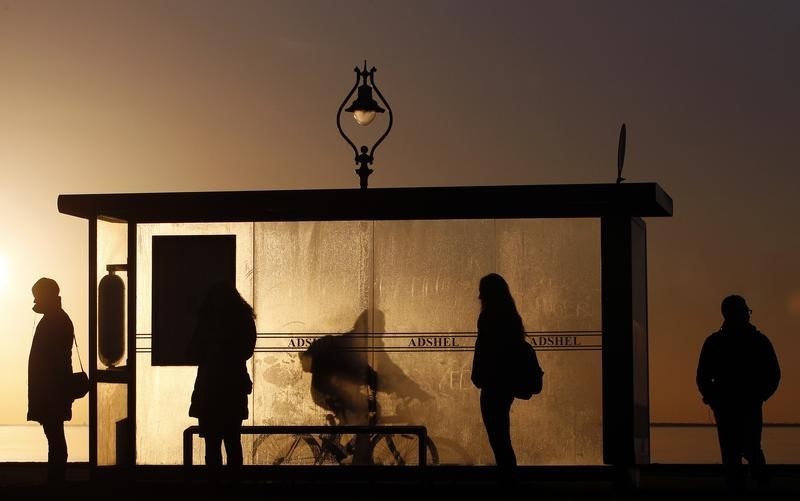 © Reuters. Commuters wait at a bus stop early in the morning near Howth in Dublin