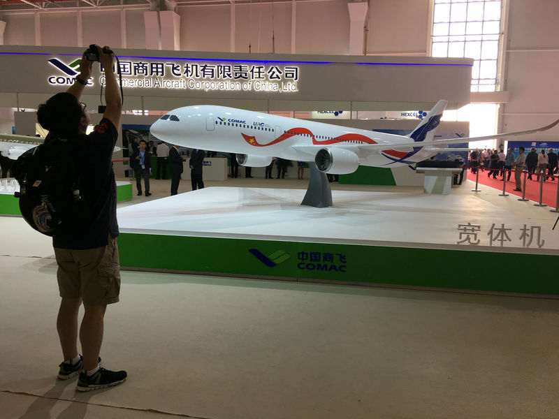 © Reuters. A man takes picture of the model of a widebody jet, which is planned to be developed by COMAC and Russia's UAC at an air show, the China International Aviation and Aerospace Exhibition, in Zhuhai