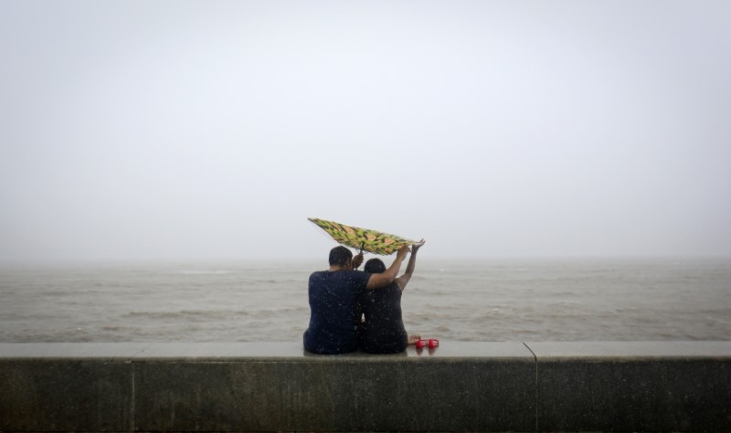 © Reuters. A couple tries to hold on to an umbrella flipped inside out at a sea front, in Mumbai