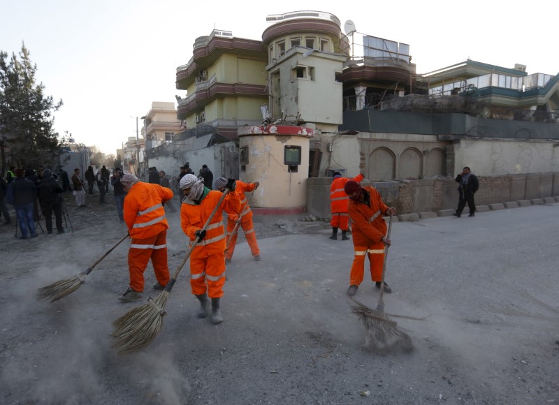 © Reuters. Afghan municipality workers sweep a road after an attack on a guest house attached to the Spanish embassy in Kabul, Afghanistan