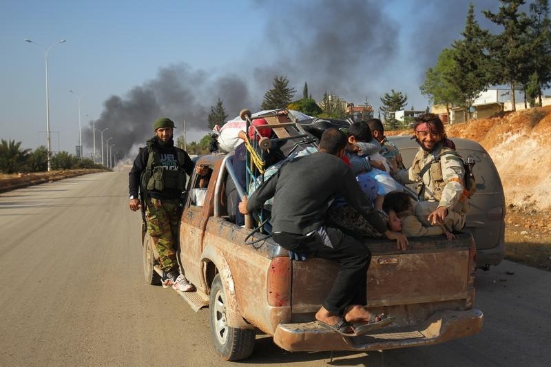 © Reuters. Rebel fighters ride a pick-up truck with civilians who fled areas of conflict in Dahiyet al-Assad, west Aleppo city