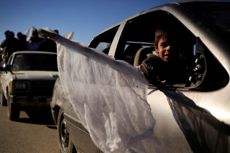 © Reuters. A boy who just fled Kokjali near Mosul carries a white flag as he sits in a car heading to a camp for the displaced, in Iraq