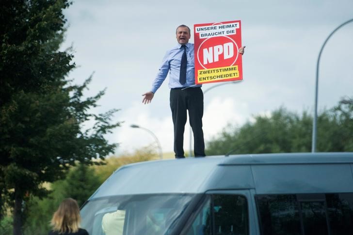 © Reuters. Udo Pastoers stands on a car during a visit by German Chancellor Angela Merkel in Greifswald