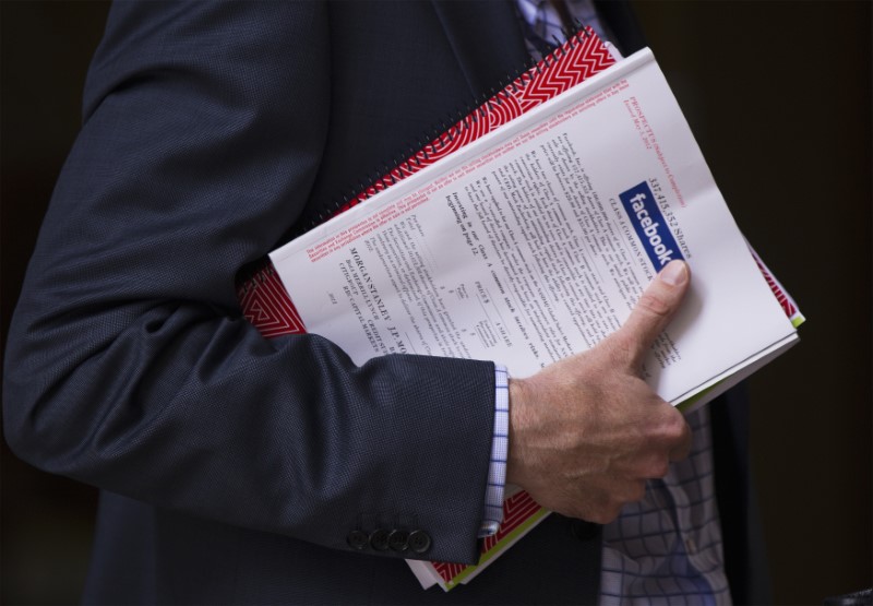 © Reuters. A man stands outside of the St. Regis hotel holding a pamphlet of information on investing in the upcoming IPO of Facebook in New York