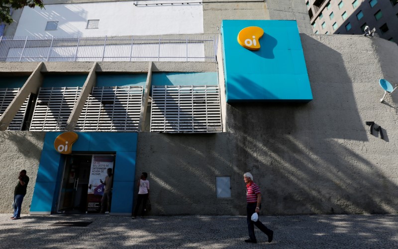 © Reuters. People walk in front of the headquarters of the Brazil's largest fixed-line telecoms group Oi, in Rio de Janeiro