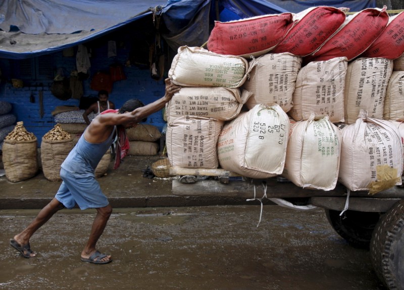 © Reuters. Labourer pushes a handcart loaded with sacks containing tea packets, towards a supply truck at a wholesale market in Kolkata, India