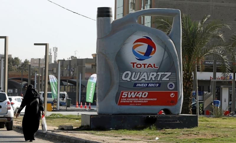 © Reuters. A woman walks past a sign for oil giant Total at a petrol station in Cairo