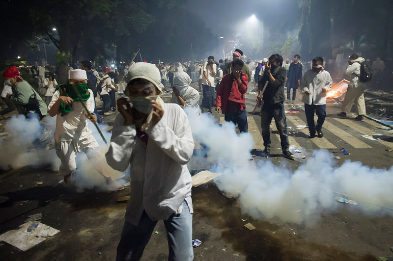 © Reuters. Muslim hardline protesters cover their faces as police fire tear gas during a protest against Jakarta's incumbent governor Basuki (Ahok) Tjahaja Purnama, an ethnic Chinese Christian running in the upcoming election, in Jakarta