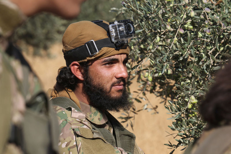 © Reuters. A rebel fighter with a camera attached to his head stands near an olive tree, western Aleppo city