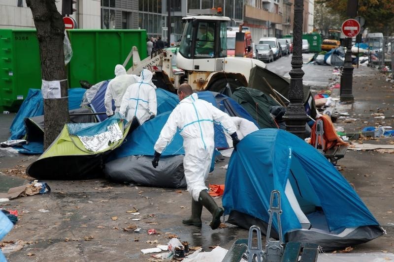 © Reuters. Funcionários limpam local de Paris após retirada de imigrantes