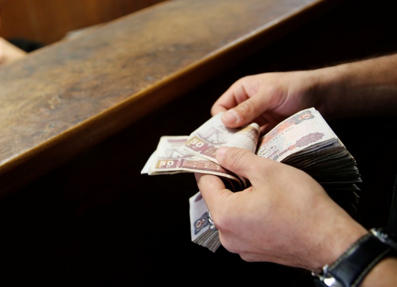 © Reuters. A customer counts his Egyptian 50 pound notes at an exchange office in downtown Cairo