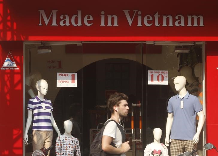 © Reuters. A tourist walks past a clothes shop in Hanoi