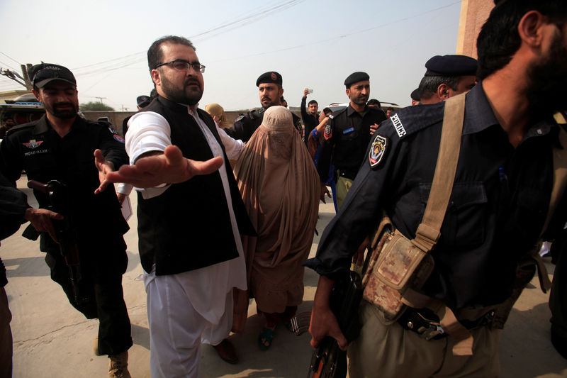 © Reuters. Policemen escort Sharbat Gula, the green-eyed Afghan woman who became a symbol of her country's wars 30 years ago when her photo as a girl appeared on the cover of National Geographic magazine, as she arrives at a court in Peshawa