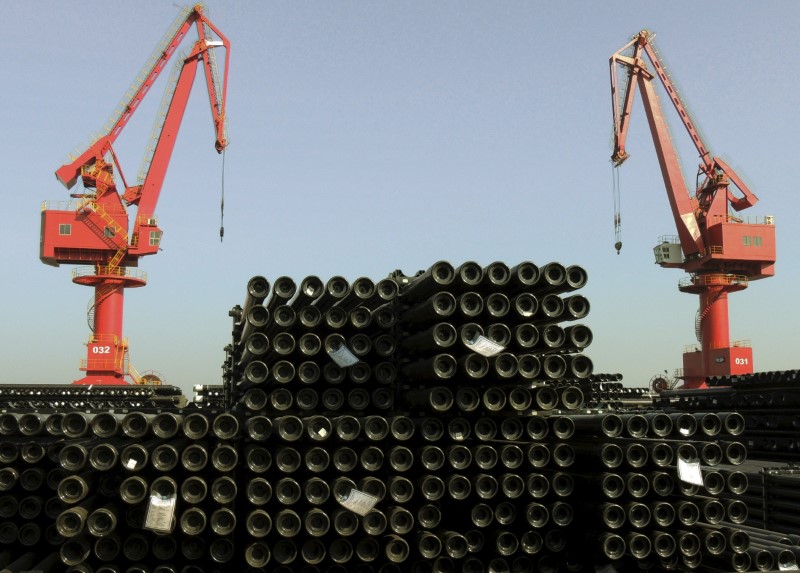 © Reuters. Cranes are seen above piles of steel pipes to be exported at a port in Lianyungang