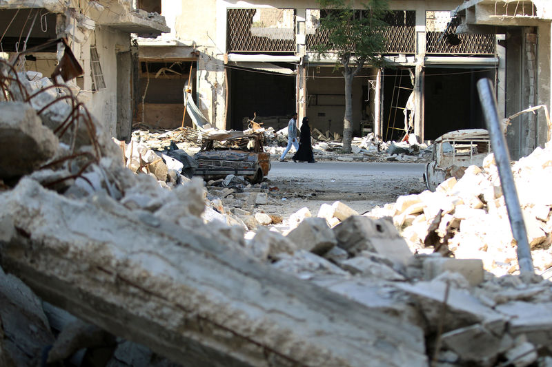 © Reuters. People walk past rubble of damaged buildings in a rebel-held besieged area in Aleppo