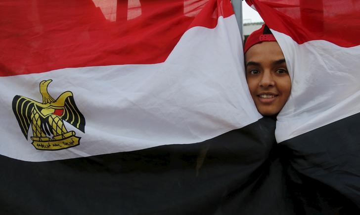 © Reuters. An Egyptian fan cheers behind the national flag before 2018 World Cup qualifying soccer match against Chad, at the Borg El Arab "Army Stadium" in Alexandria