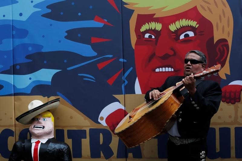 © Reuters. A member of the mariachi plays music next to a pinata depicting U.S. Republican presidential nominee Trump during a campaign encouraging U.S. citizens in Mexico to register to vote against Trump, in Mexico City